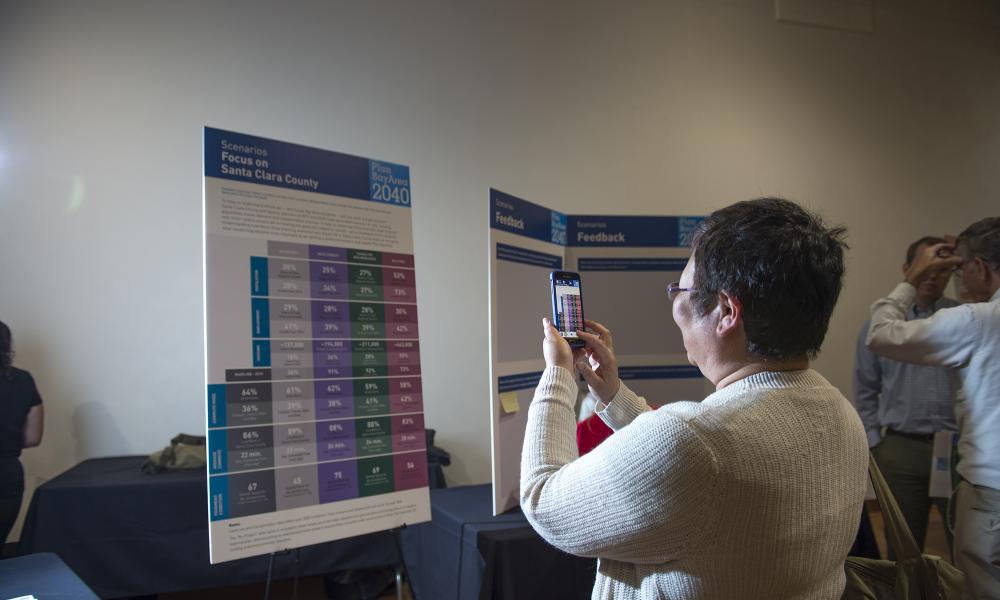 A participant records an information display with her smartphone at the Santa Clara County Plan Bay Area public outreach meeting at the Tech Museum in San Jose, 5-26-16