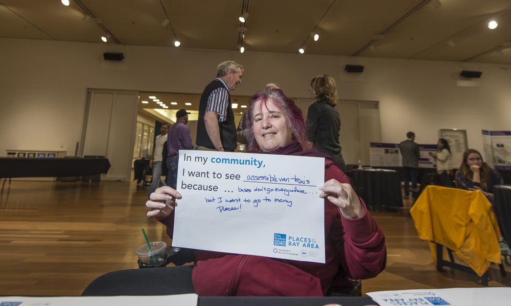 A member of the public shows the sign she created at the Santa Clara County Plan Bay Area public outreach meeting at the Tech Museum in San Jose, 5-26-16